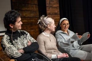 Tre personer sitter på en scene og snakker